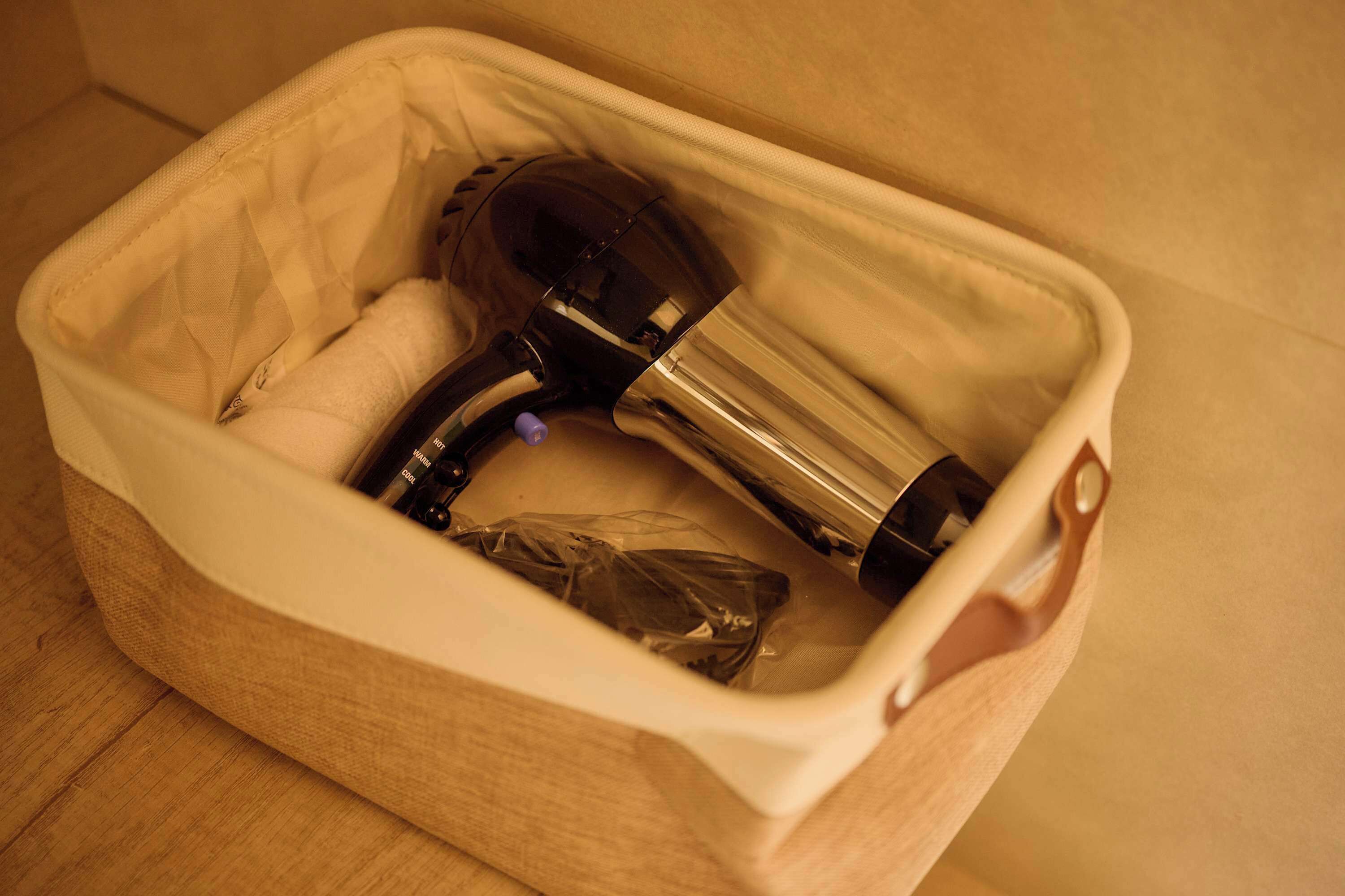 A storage bin with a handle, containing a black object and a clear plastic bag.