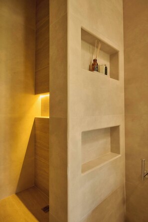 Une salle de bain moderne avec des étagères encastrées, un espace douche et un luminaire.