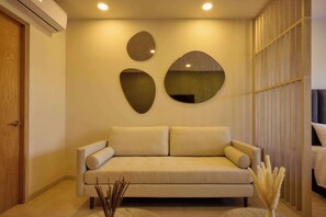 A neutral-toned sofa with a cushion, a wall-mounted mirror, and a decorative vase with dried plants. - Stylish Loft in Historic Oaxaca | Walk to Zócalo (Oaxaca de Juárez)