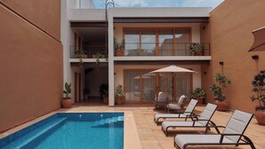 Un bâtiment moderne doté d’une piscine, de chaises longues et de plantes en pot.