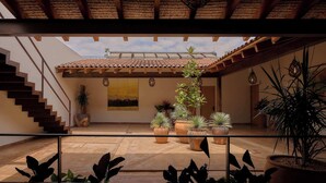 Un patio couvert avec un toit en tuiles, des plantes en pot et un escalier.