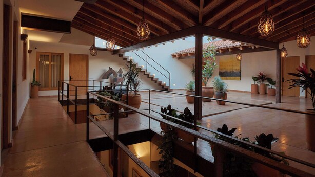 Un intérieur spacieux avec un plafond en bois, un escalier et des plantes en pot.