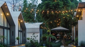 A modern building with a paved courtyard, string lights, and outdoor seating. - Casa Samadhi - Villa #5 Padme para dos (Atlixco)
