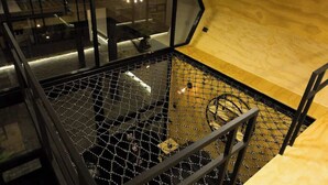 A high-ceilinged room with a glass wall, a wooden floor, and a metal railing. - Casa Samadhi - Villa #5 Padme para dos (Atlixco)