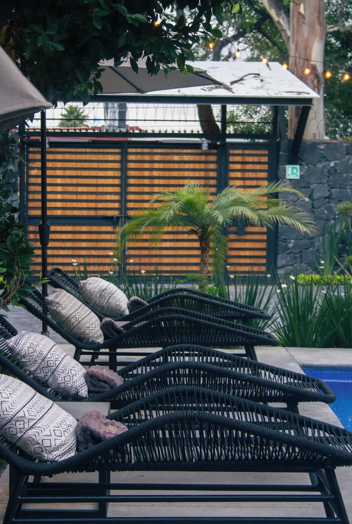 Un espace aménagé au bord de la piscine, avec des chaises longues, une pergola et un mur en pierre.
