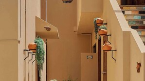 A narrow alleyway with a staircase leading to a door, flanked by walls with hanging planters and a hanging light fixture. - Comfortable Apartment with Pool & Outdoor Oasis (Puerto Escondido)
