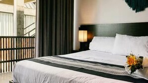 A modern hotel room with a large bed, a balcony, and a view of the building's interior. - Boutique Retreat Near Beach w/ Pool & Garden (Puerto Escondido)