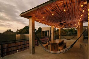 An outdoor seating area with a bamboo roof, concrete pillars, and a hammock. - Boutique Retreat Near Beach w/ Pool & Garden (Puerto Escondido)