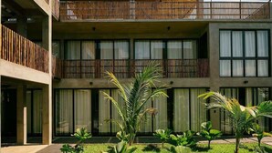 A modern building with a two-story balcony, large windows, and a well-maintained garden with various plants. - Boutique Retreat Near Beach w/ Pool & Garden (Puerto Escondido)