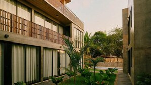 A modern building with a balcony, large windows, and a garden area with plants. - Boutique Retreat Near Beach w/ Pool & Garden (Puerto Escondido)