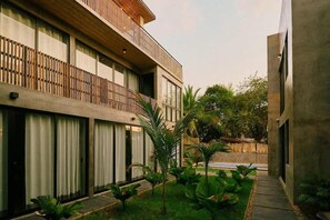 A modern building with a balcony, large windows, and a garden area with plants. - Boutique Retreat Near Beach w/ Pool & Garden (Puerto Escondido)