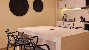 A modern kitchen with a central island, black chairs, and a light-colored countertop. - Stylish King Apartment in Oaxaca's Reforma District (Oaxaca de Juárez)