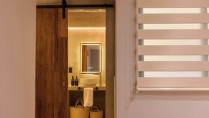 Uma casa de banho moderna com porta de madeira, espelho, lavatório e porta-toalhas.
