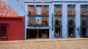 Um edifício com fachada azul, varandas e uma vitrine com uma placa que diz 'El Aguil'.