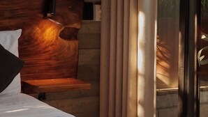 Un lit avec une tête de lit en bois, un oreiller blanc et une couvre-lit à motifs.