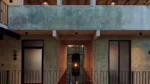 A two-story building with a balcony, a thatched roof, and a central seating area with chairs and tables. - Stylish Apartment 2 Blocks from Punta Zicatela Beach (Puerto Escondido)