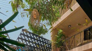 Spazio interno su più livelli con una fontana centrale, circondato da piante in vaso e una struttura muraria geometrica.