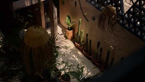 Un cortile con piante in vaso, un lampadario appeso e un muro in mattoni.