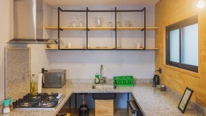 Una cocina compacta con estufa a gas, microondas y estantes de madera sobre el fregadero.