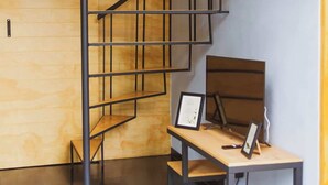 Una escalera de caracol con detalles de madera y barandillas de metal, que lleva a un nivel superior.