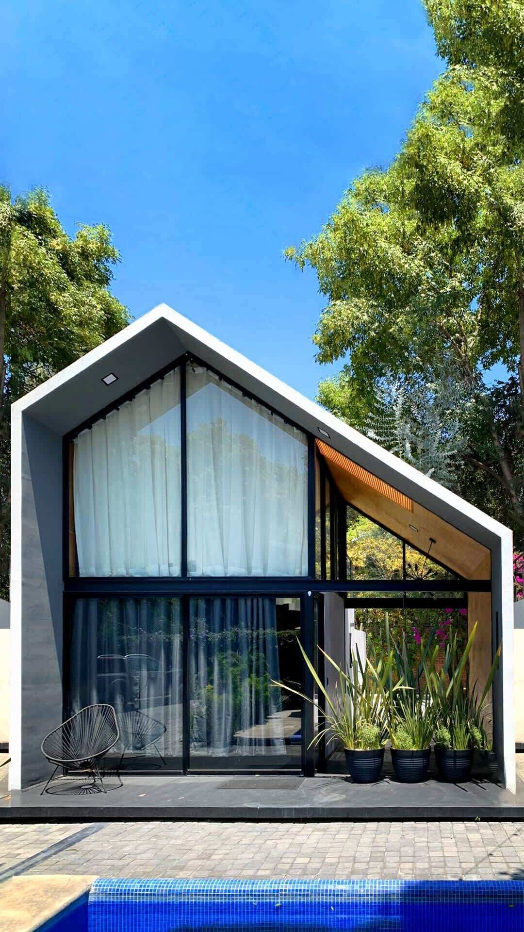 A modern house with a large glass window, a pool, and potted plants.
