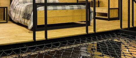 A room with a bed, a wall-mounted air conditioner, and a wooden ceiling.