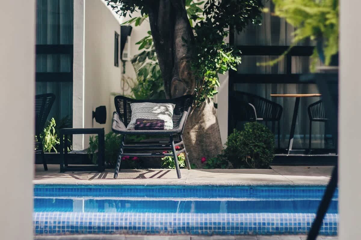 A poolside area with a lounge chair, a small table, and a potted plant.