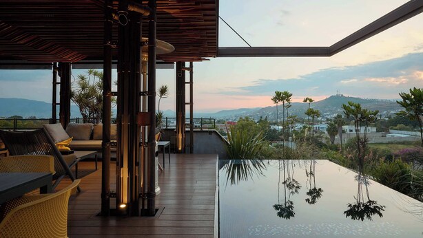 Un espace de détente extérieur moderne, doté d’une piscine, d’une terrasse en bois et offrant une vue sur le paysage.