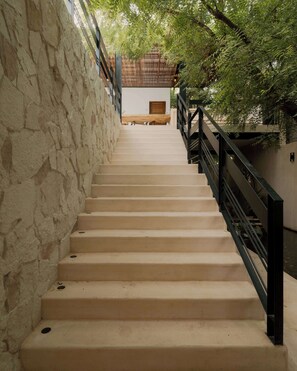 A staircase with beige steps, a stone wall on one side, and a wooden fence on the other. - Oceanview King Suite w/ Soaking Tub & Rooftop Terrace (Puerto Escondido)