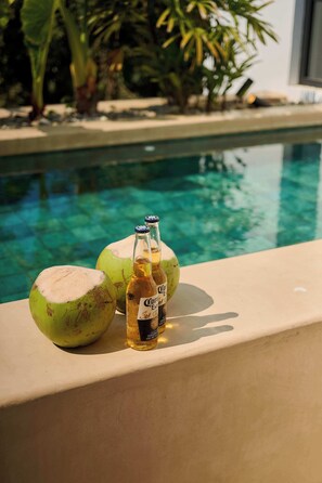 A poolside setting with a beverage bottle and two coconuts. - Oceanview King Suite w/ Soaking Tub & Rooftop Terrace (Puerto Escondido)