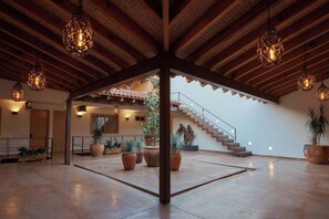 A spacious indoor area with a wooden ceiling, potted plants, and a staircase.