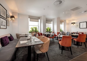 A modern dining area with multiple tables and chairs, large windows, and indoor plants. - Elegant historic Edinburgh apartment with space for ten in a prime city location (Edinburgh)