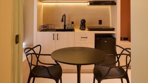 A modern kitchen with a microwave, stove, and sink. There is a dining table with four chairs. - Stylish King Apartment in Oaxaca's Reforma District (Oaxaca de Juárez)