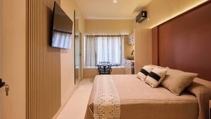 A bedroom with a bed, a ceiling fan, a TV, a window with curtains, and a desk with a chair. - Stylish King Apartment in Oaxaca's Reforma District (Oaxaca de Juárez)
