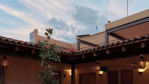 Une cour agrémentée de plantes en pot, une pergola et un bâtiment doté d’un toit en tuiles.