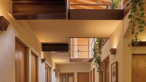 Un couloir avec des portes en bois, des plantes en pot et un plafond orné d’un motif tissé.