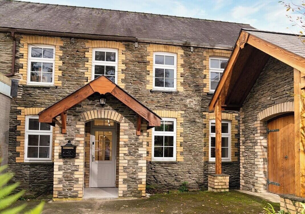 Un bâtiment en pierre avec une entrée centrale, de nombreuses fenêtres et une porte en bois.