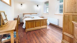 Un dormitorio con una cama, un aparador, una mesa y un ventanal de madera.