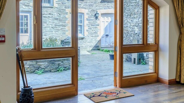A room with a large arched doorway leading to a courtyard, a wooden floor, and a doormat. - Weavers Rest offers beautifully crafted accommodation in a magnificent area of Wales (Llandysul)