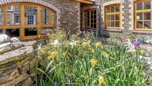 A stone building with large windows and a garden with daffodils. - Weavers Rest offers beautifully crafted accommodation in a magnificent area of Wales (Llandysul)