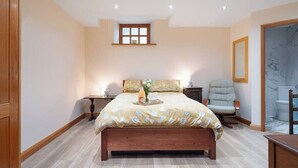 A bedroom with a large bed, bedside tables, a chair, a window, and a door. - Weavers Rest offers beautifully crafted accommodation in a magnificent area of Wales (Llandysul)