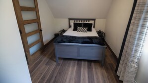 A bedroom with a bed, bedside tables, a wooden ladder, and a curtain.