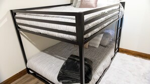 A bunk bed with a striped mattress, pillows, and a folded blanket.