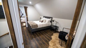 A bedroom with a bed, bedside lamps, a fur rug, and a view of the outside.