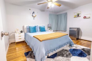A bedroom with a bed, nightstand, lamp, and a ceiling fan.