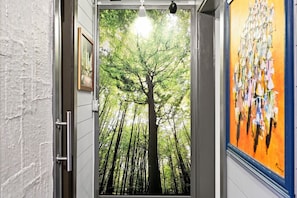 A hallway with a door leading to a forest view. - The Steele Mill + Loft (Indianapolis)