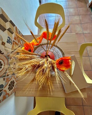 Una silla con un arreglo decorativo de espigas de trigo y flores naranjas.