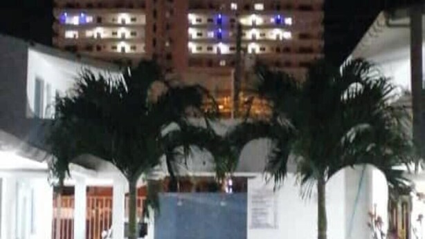 A multi-story hotel with a central atrium, palm trees, and a swimming pool.