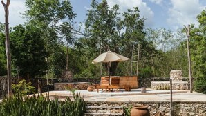 Un espace extérieur aménagé avec des marches en pierre, du mobilier en bois et un grand parasol.