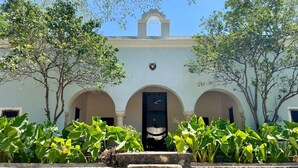 A building with three arches, a central door, and a small balcony with a railing. - Cuch Balam Private Estate with 3 Bedrooms, 2 Hectares of Garden, Pool and Cenote (Chunkanán)